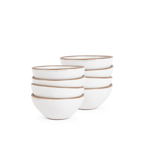A stack of 8 small dessert sized rounded ceramic bowls in a cool white color featuring iron speckles and an unglazed rim