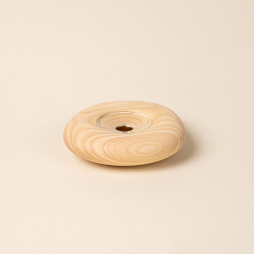 Large round light wood candle holder with visible grain and a glass insert in the center, displayed against a neutral background.