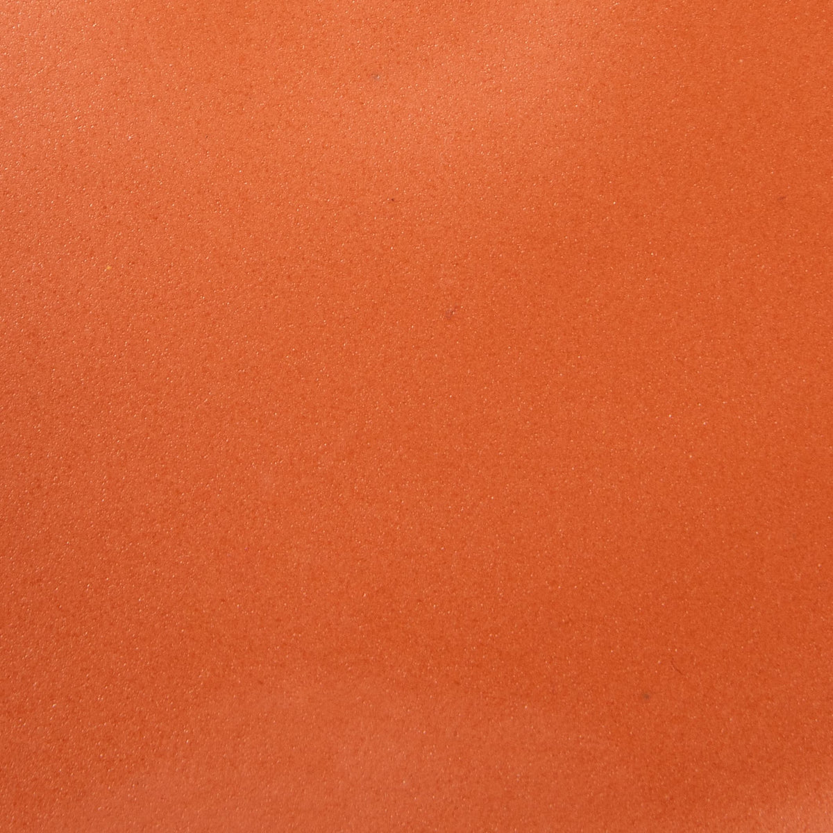 A closeup of a ceramic plate in a bold orange color