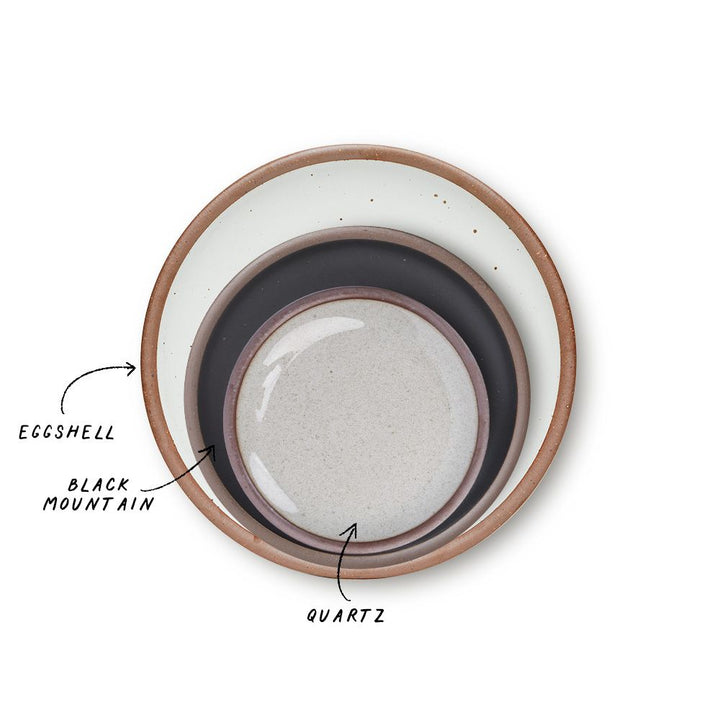 A stack of 3 plates in Dinner, Side, and Cake sizes in a cool white, graphite black, and reflective icy white colors.