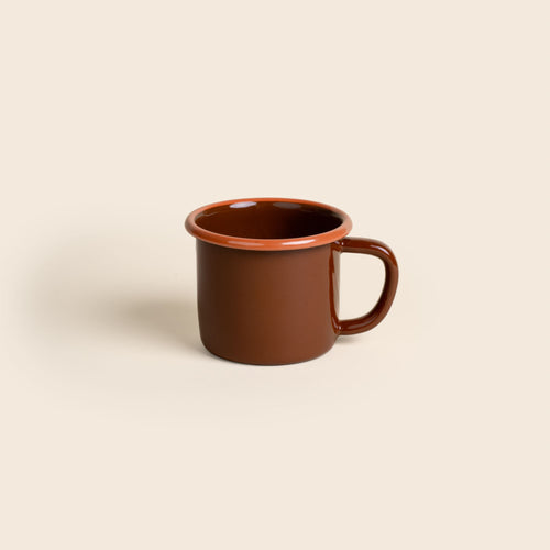 A red-brown enamel mug with an orange rim and handle, shown against a neutral beige background.