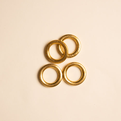 Four round, textured gold rings arranged in an overlapping cluster on a neutral background.