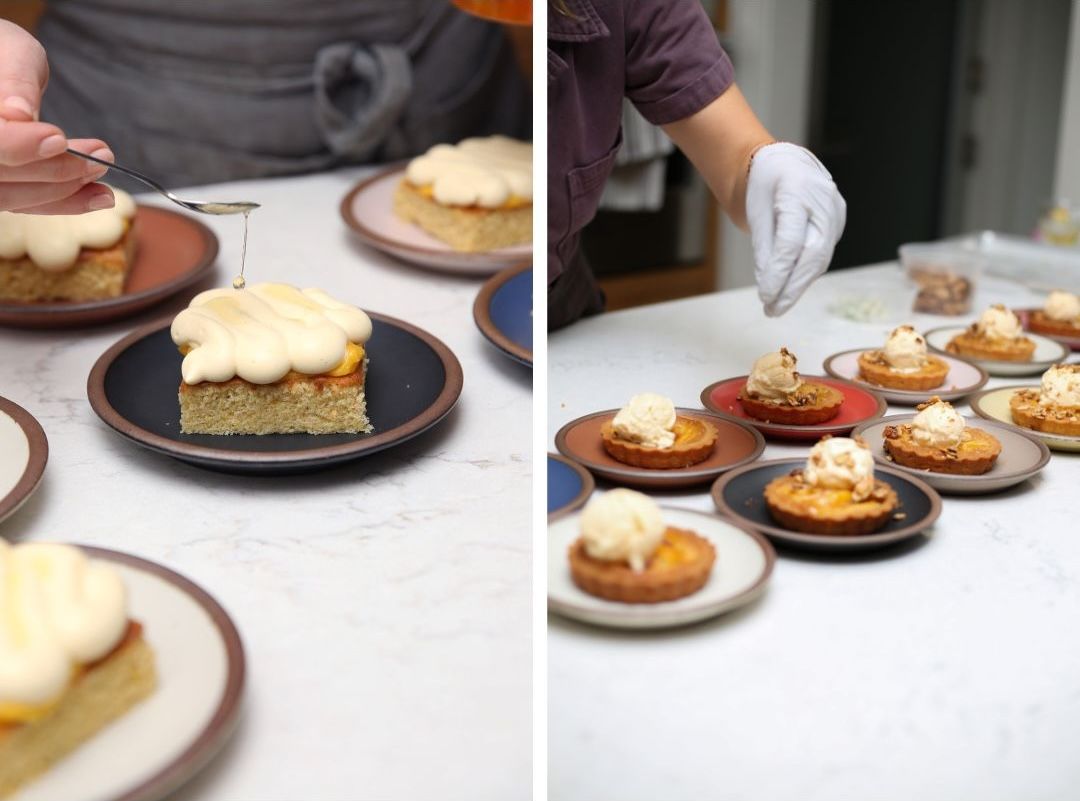 Two photos: The left is a hand pouring a glaze over a dessert on a small black cake plate. The right is a hand topping some crumble over desserts lined up on rows of cake plates.