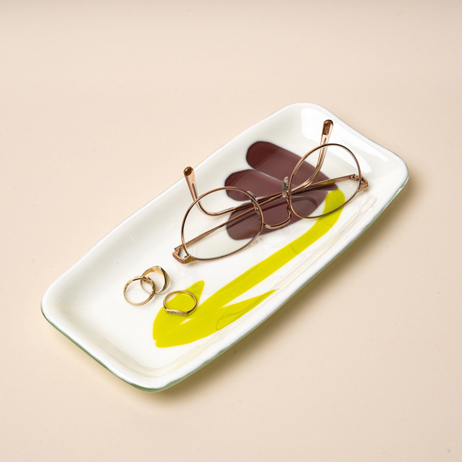 A white rectangular glass catchall tray with a design featuring a minimal purple flower with green stem.