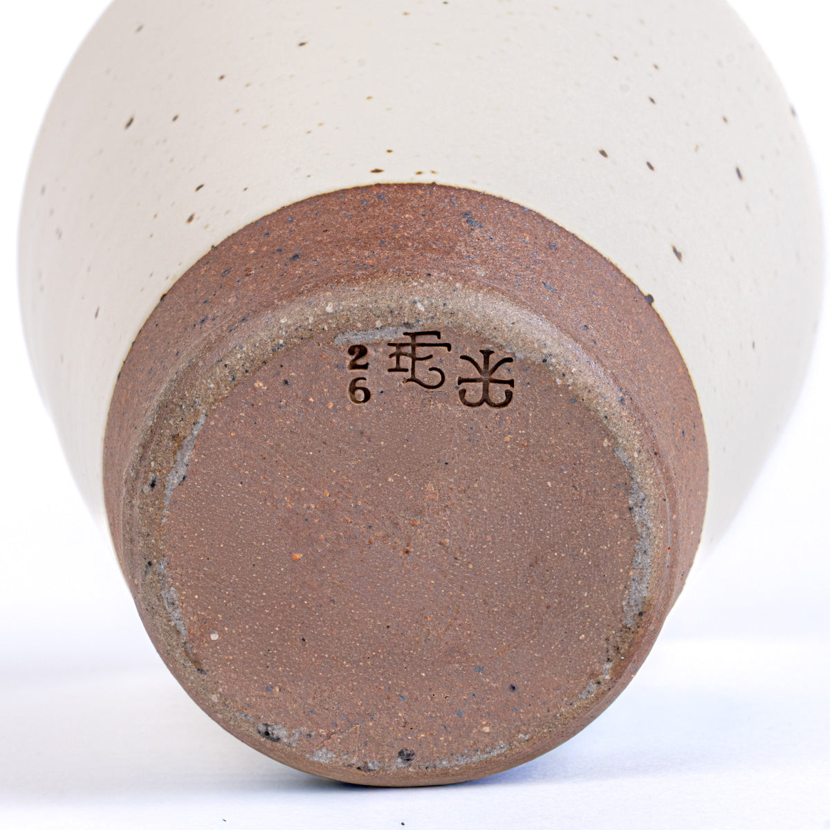 Bottom of a wheel thrown cup in an off-white color with stamps that read '26' 'EF' and John Vigeland's stamp.