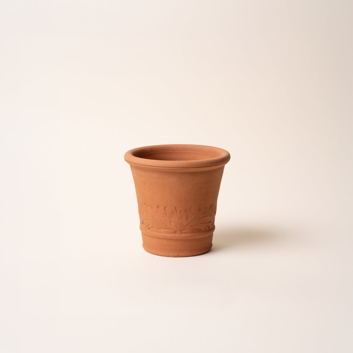 Small terracotta planter with embossed botanical band detail displayed against a neutral background.