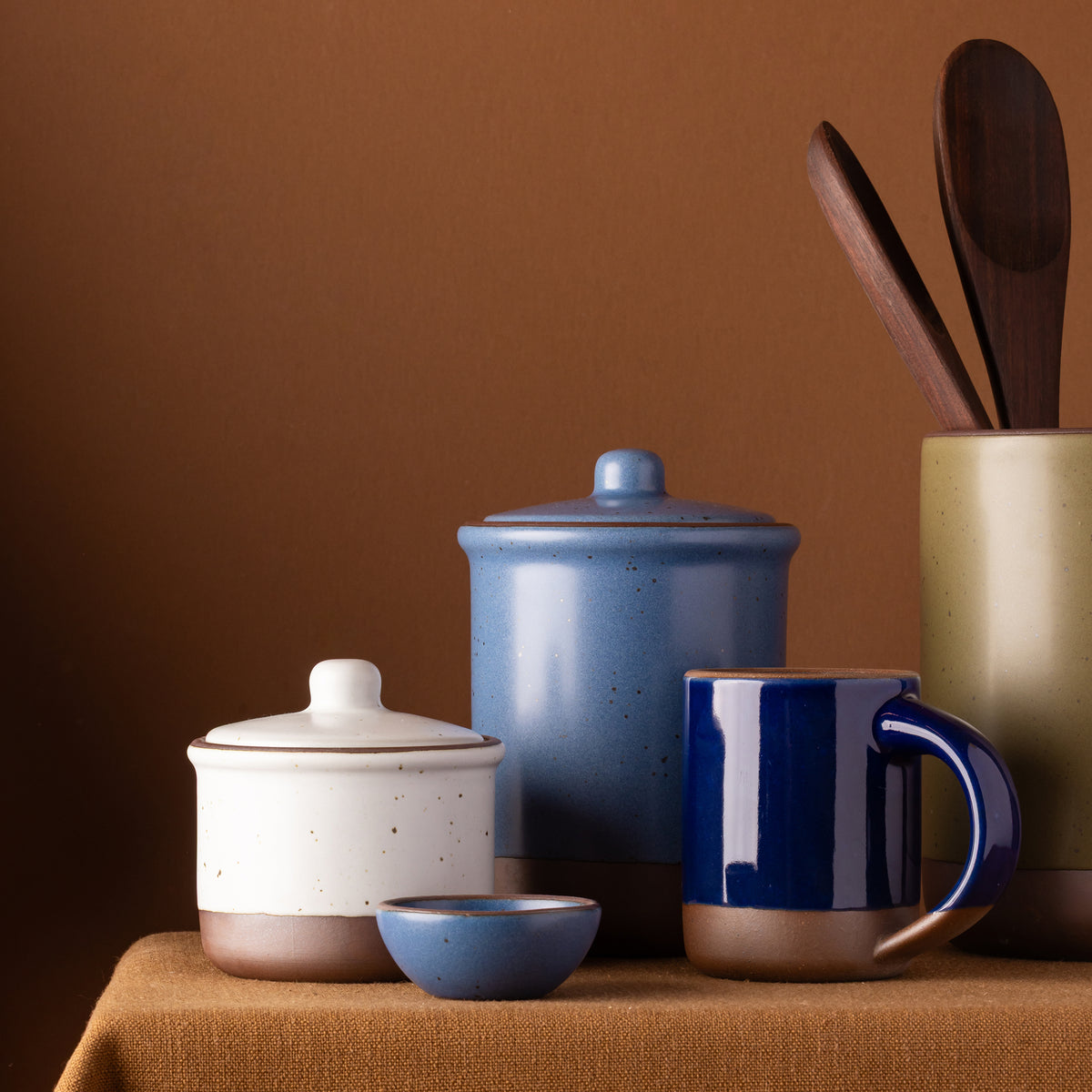 Ceramic Utensil Jar, Tall Jar, and Small Jar, Bitty Bowl and Mug all arranged on a tablecloth.