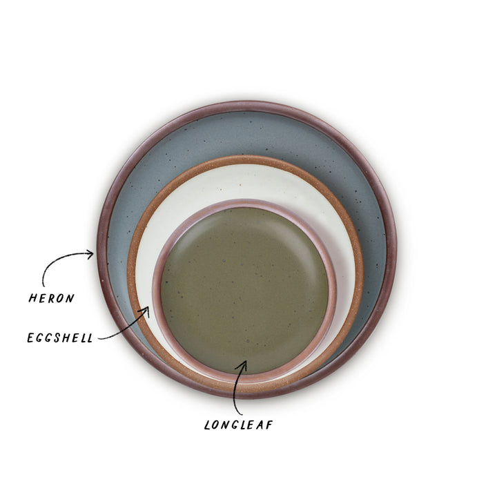 Three nested ceramic plates with different colors, blue-grey, cool white, and olive green with labels on a white background