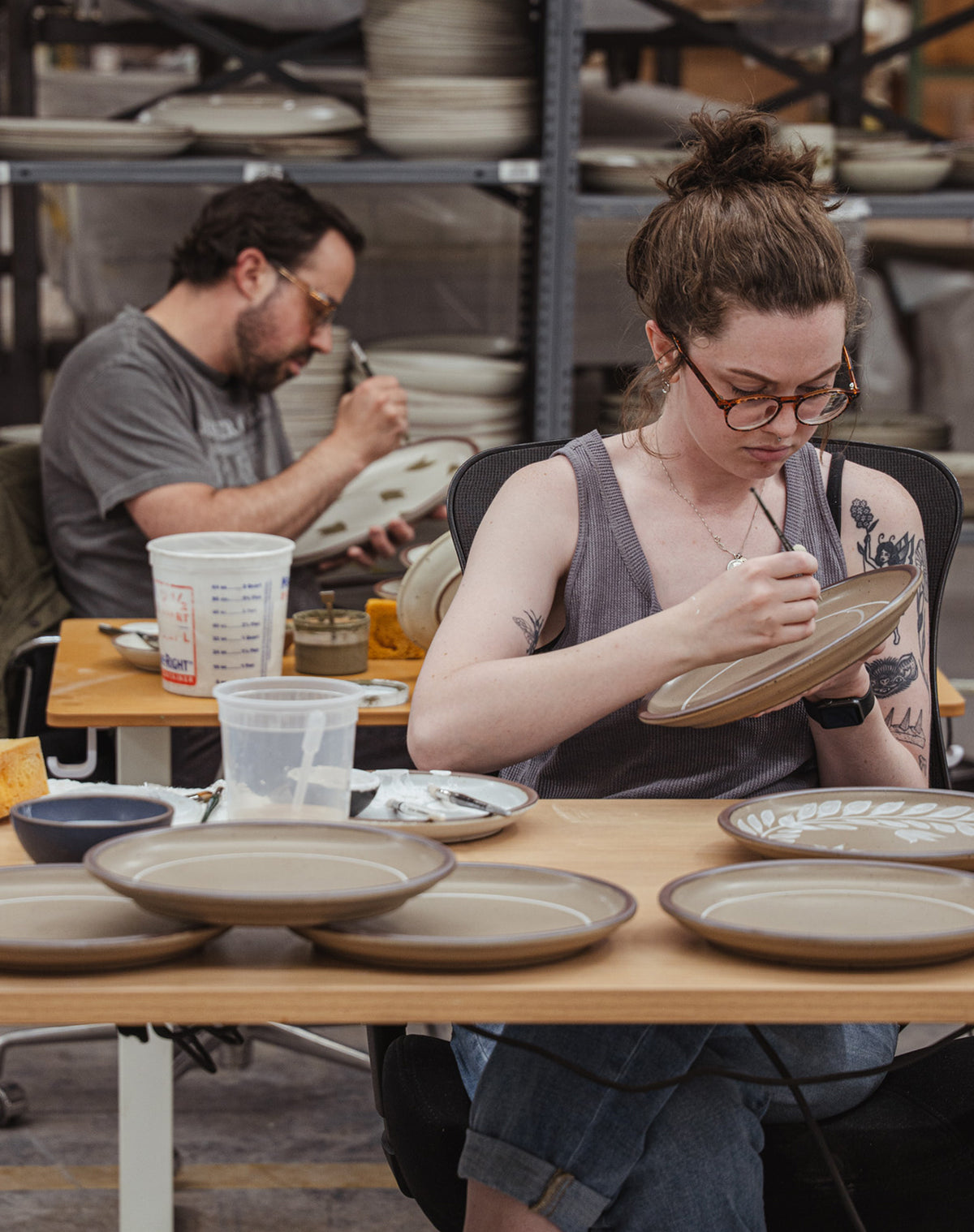 Alex and Rachel painting ceramic plates in the pottery factory.