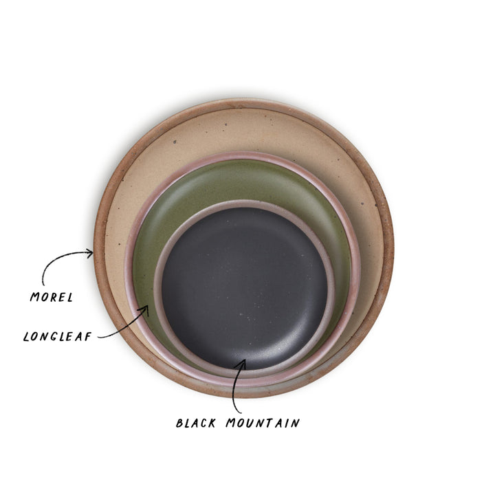 Three nested ceramic plates with different colors, pale light brown, olive green, and graphite black with labels on a white background