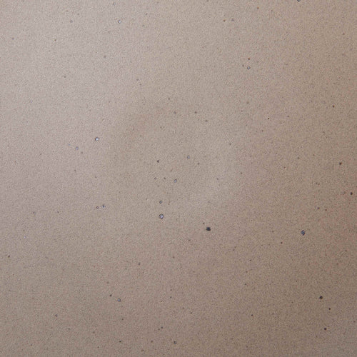 A closeup of a ceramic plate in a warm, pale brown color featuring iron speckles