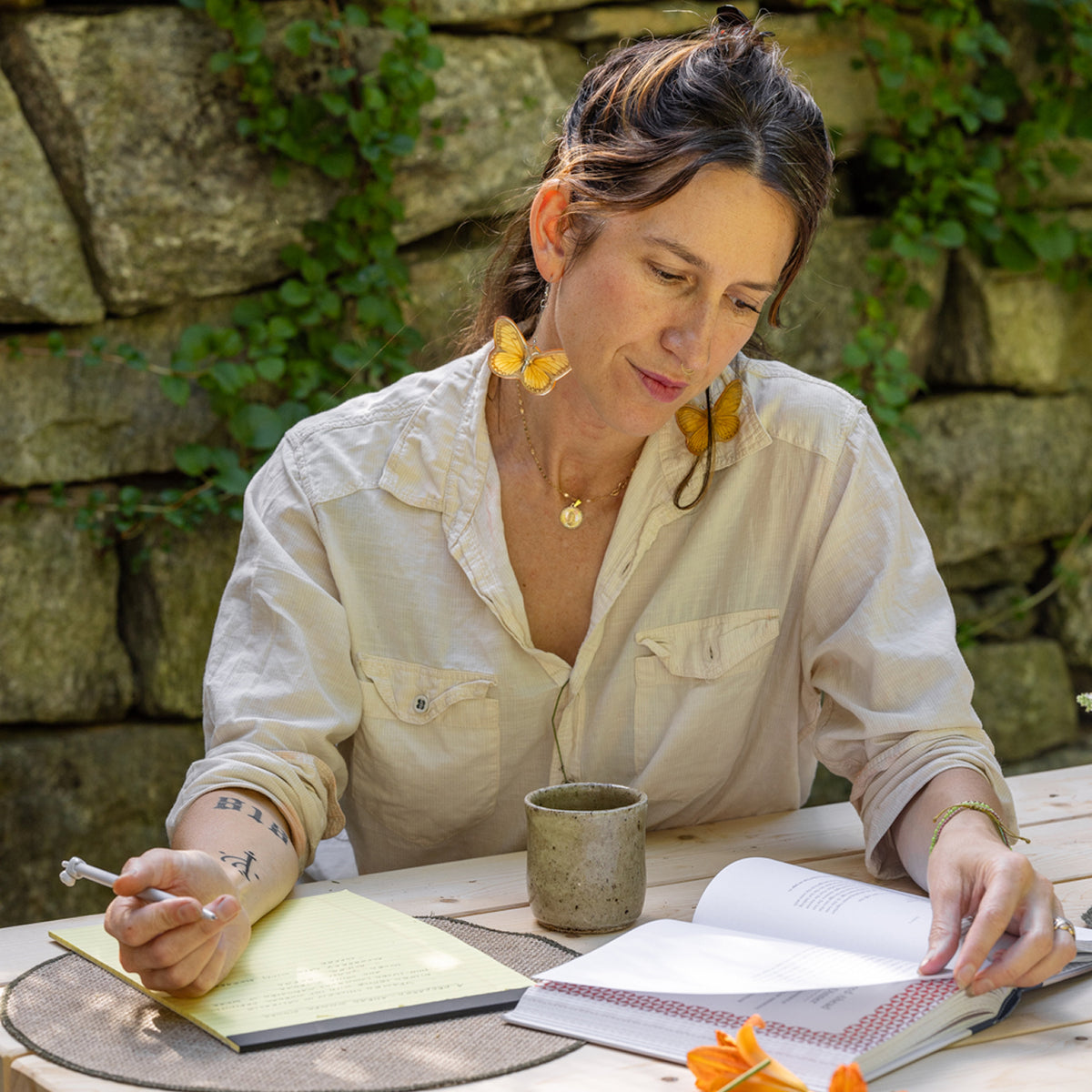 Connie sitting at a table outside reading Taste of Country Cooking and writing on a yellow notepad