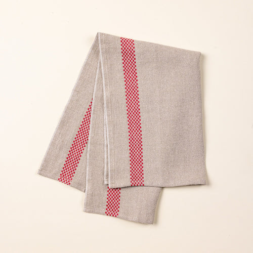 A folded linen towel in a beige color with a red checkerboard stripe down the side