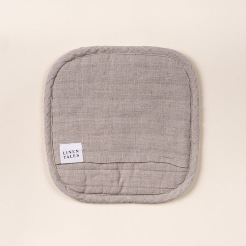 Square quilted linen potholder in a natural color with rounded corners and a small ‘LINEN TALES’ label, on a light background.