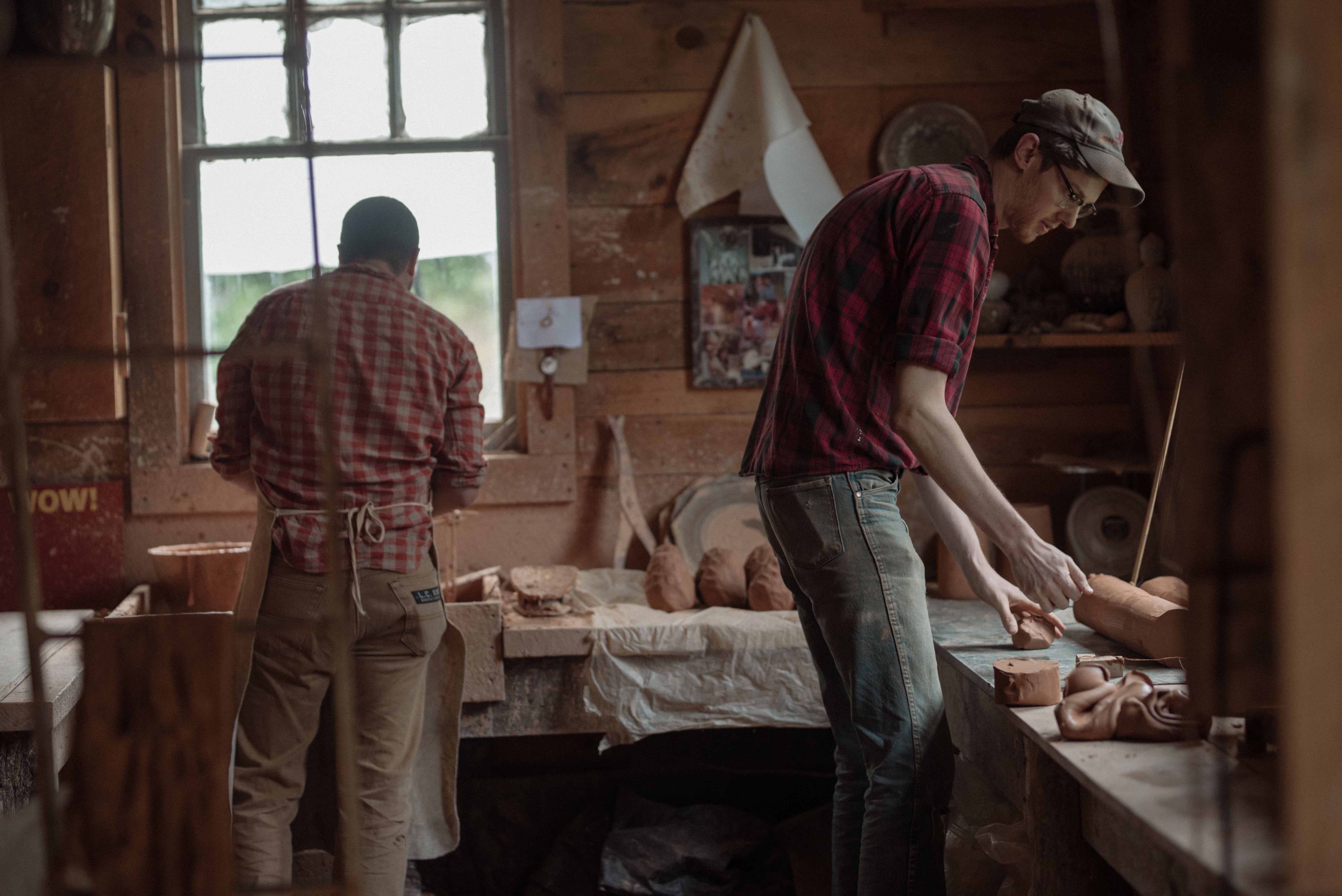 Alex and John stand throwing pots in the original workshop