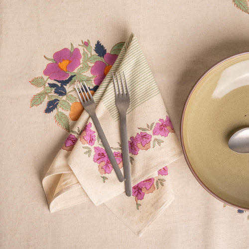 Floral and green-striped linen napkin folded with silverware and next to a grey-green plate.