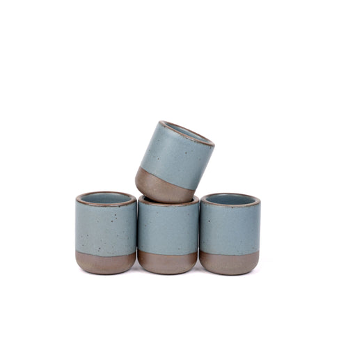 A set of 4 small, short ceramic mug cups in a blue-grey color featuring iron speckles and unglazed rim