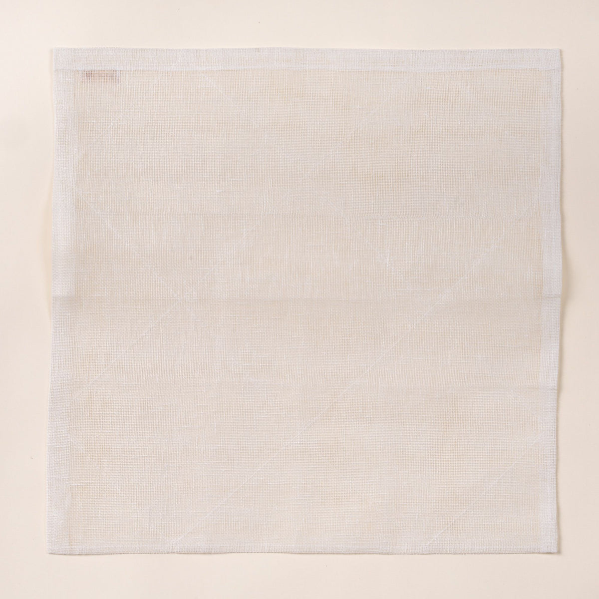 Square white linen cleaning cloth laid flat on a light background, showing a subtle woven texture and stitched edges.