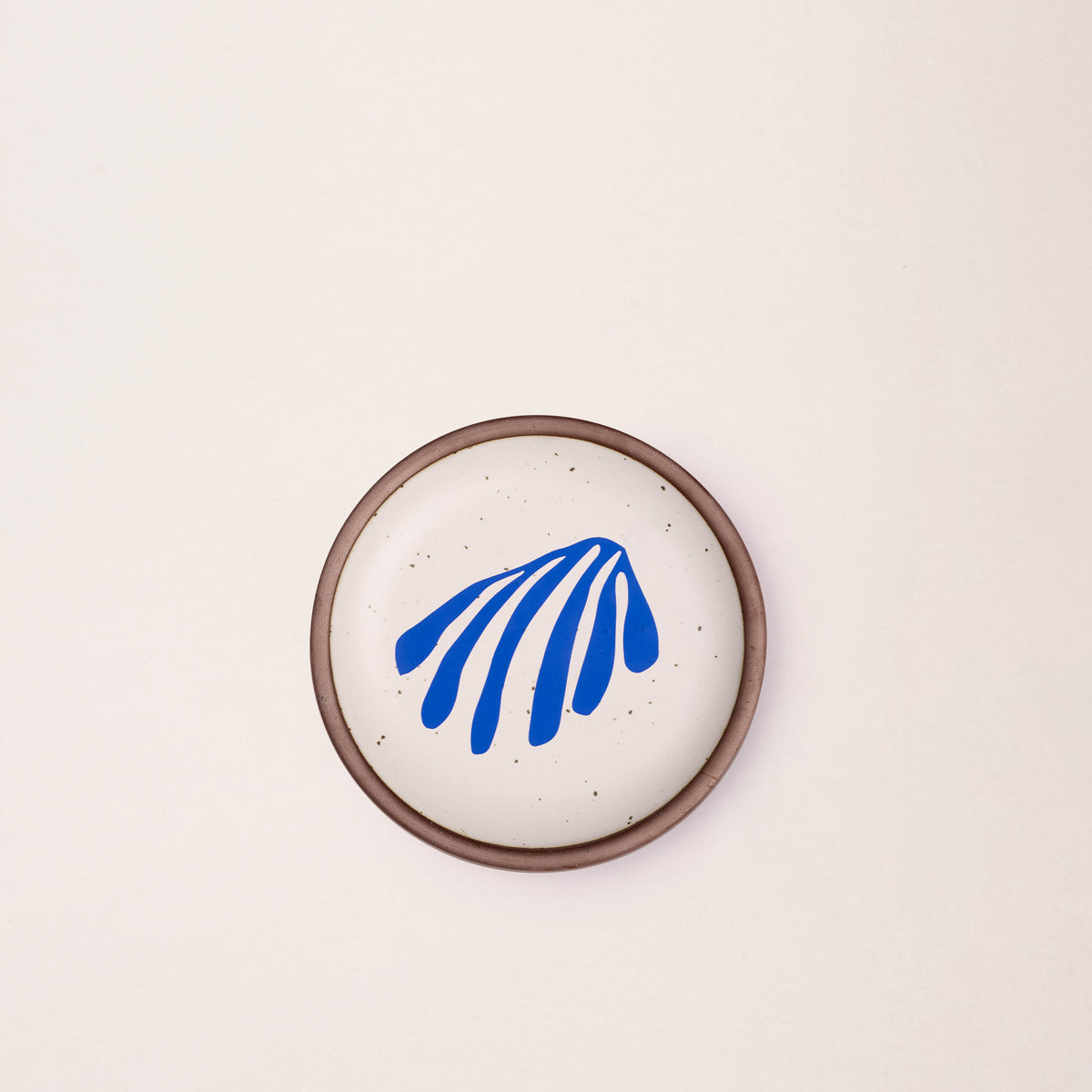 A ceramic dessert sized plates in a warm off-white color with unglazed rim, a frond-like cut-outs from Henri Matisse’s La Perruche et la sirène.