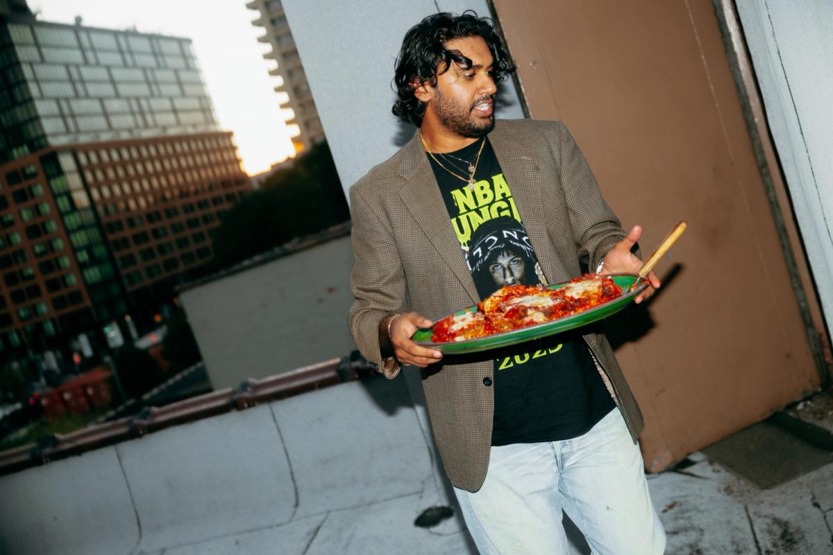 A man on a rooftop holding a platter of food.