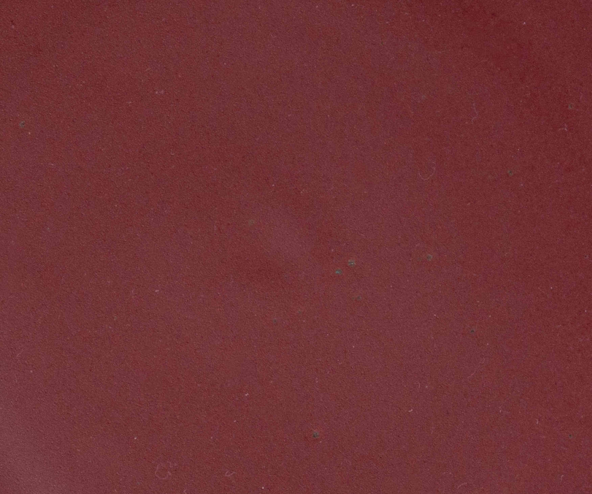A closeup of a ceramic plate in a berry plum color featuring iron speckles