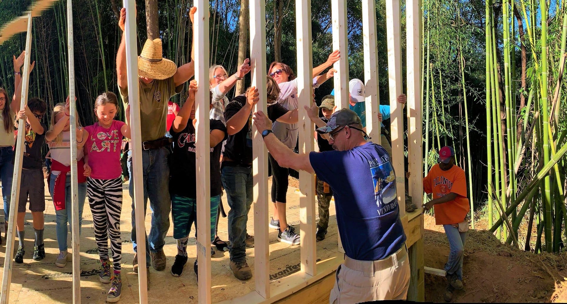 Multiple people outside framing a wall for a home that is being constructed.