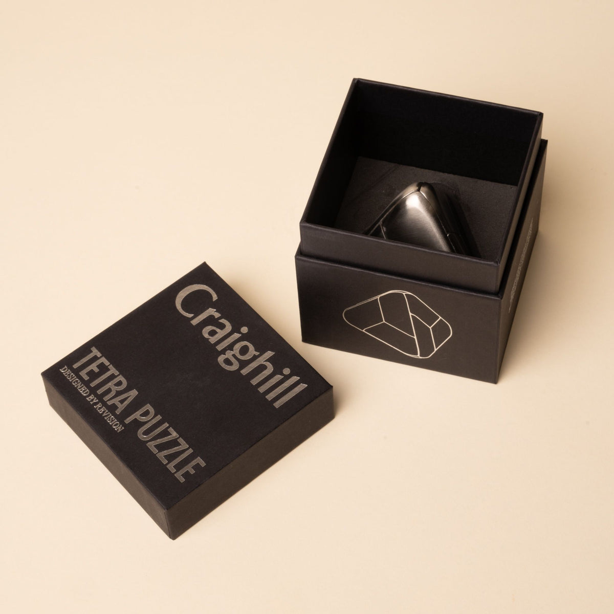 Open black box with "Craighill Tetra Puzzle" printed on the lid, revealing a triangular metal puzzle inside.
