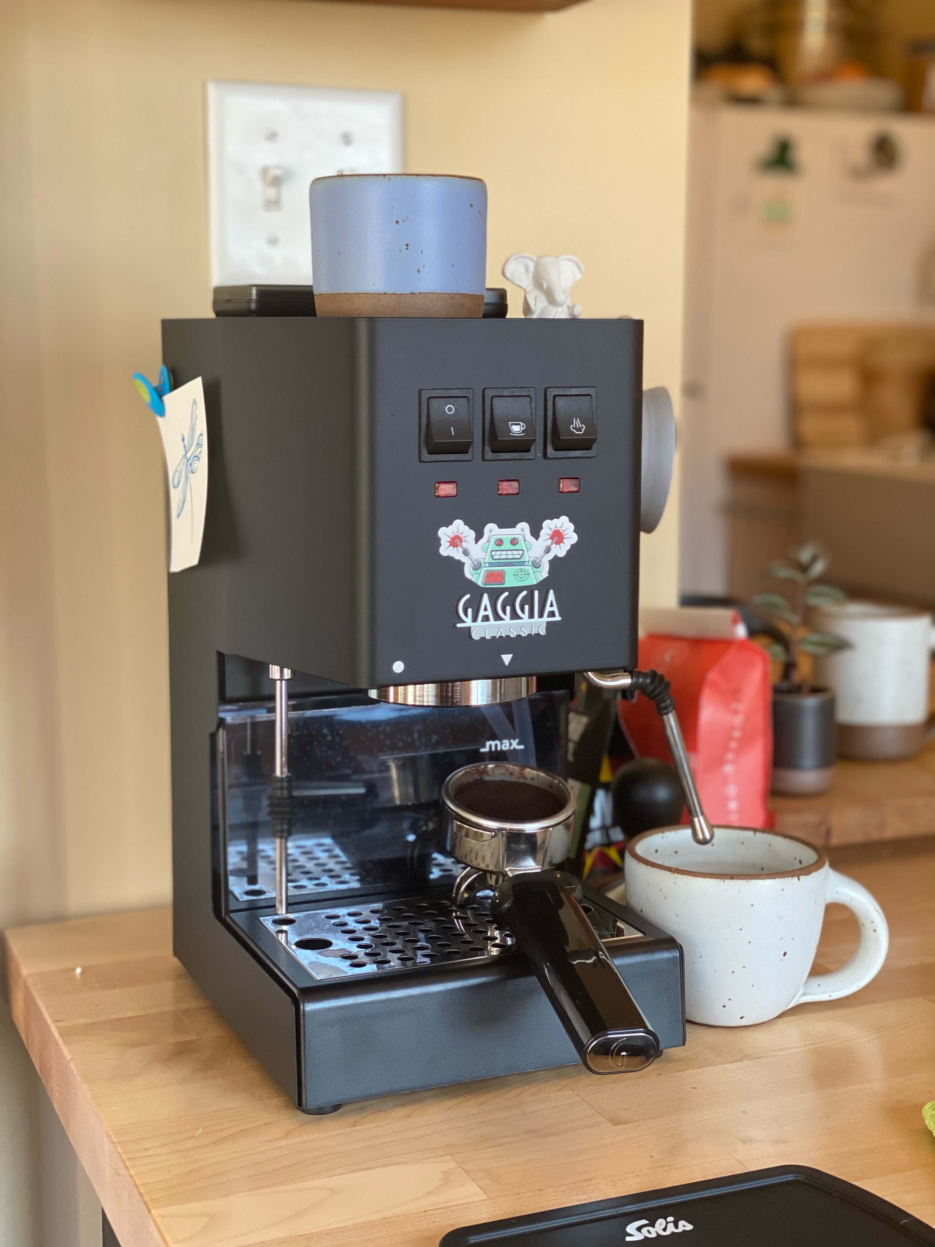 A Gaggia Classic Pro in Matte Black with a cream mug