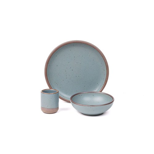 A small tiny cup, a medium sized plate, and a small breakfast bowl paired together in a blue-grey color featuring iron speckles.