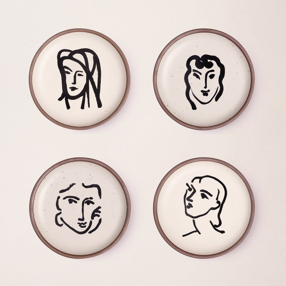 Four ceramic medium-sized plates in a warm off-white color with unglazed rim, featuring black aquatint portrait artworks by Henri Matisse.