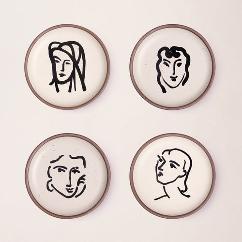 Four ceramic medium-sized plates in a warm off-white color with unglazed rim, featuring black aquatint portrait artworks by Henri Matisse.