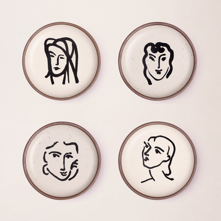 Four ceramic medium-sized plates in a warm off-white color with unglazed rim, featuring black aquatint portrait artworks by Henri Matisse.
