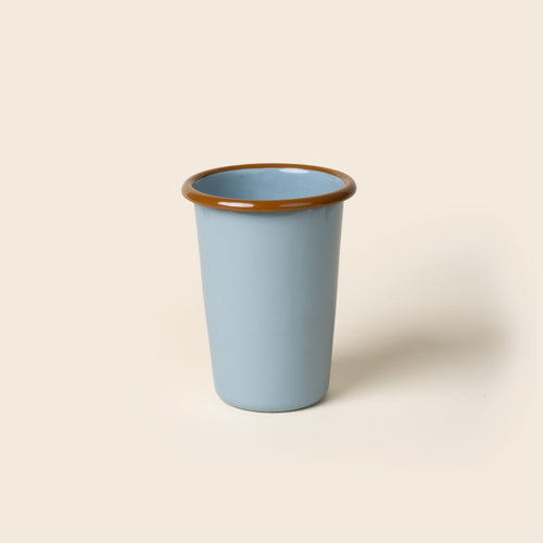 A tall robin's egg blue enamel tumbler with a glossy brown rim, set against a soft beige background.