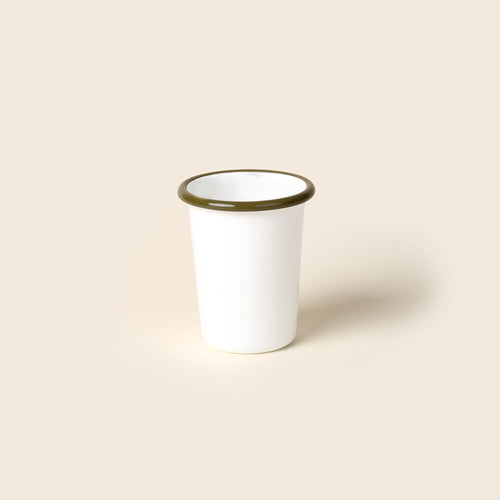 A short white enamel tumbler with an olive green rim, set against a soft beige background.