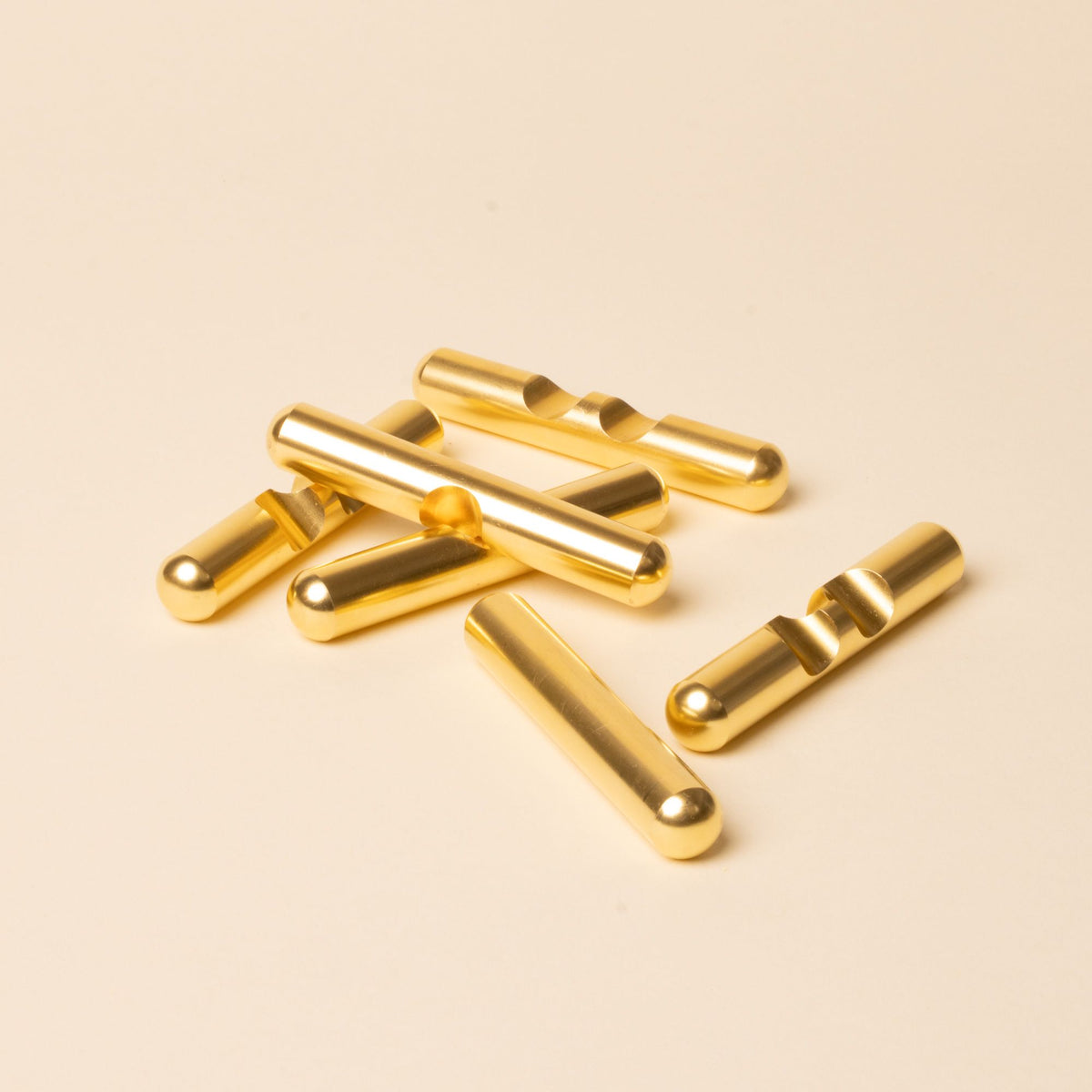 Six gold puzzle pieces with rounded edges arranged loosely on a beige surface.