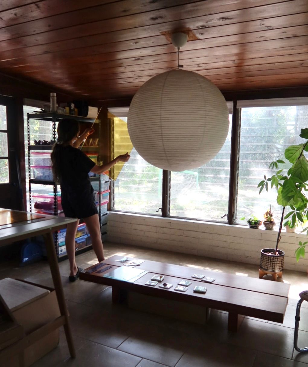 Carley in her studio holding a large piece of glass
