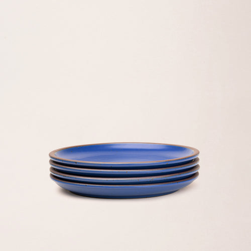 4 dinner sized ceramic plates in a cobalt blue color featuring iron speckles and an unglazed rim