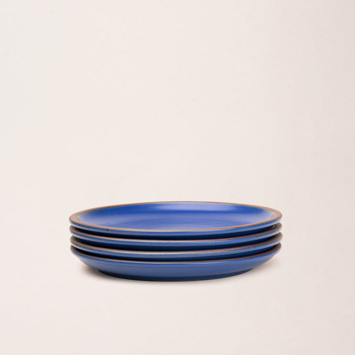 4 dinner sized ceramic plates in a cobalt blue color featuring iron speckles and an unglazed rim