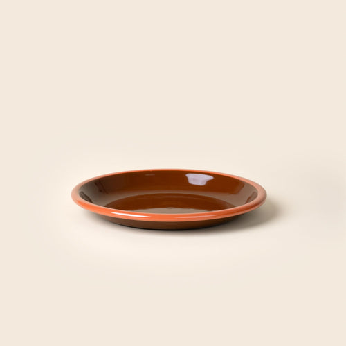 A simple enamel side plate in dark brown-red with an orange rim.
