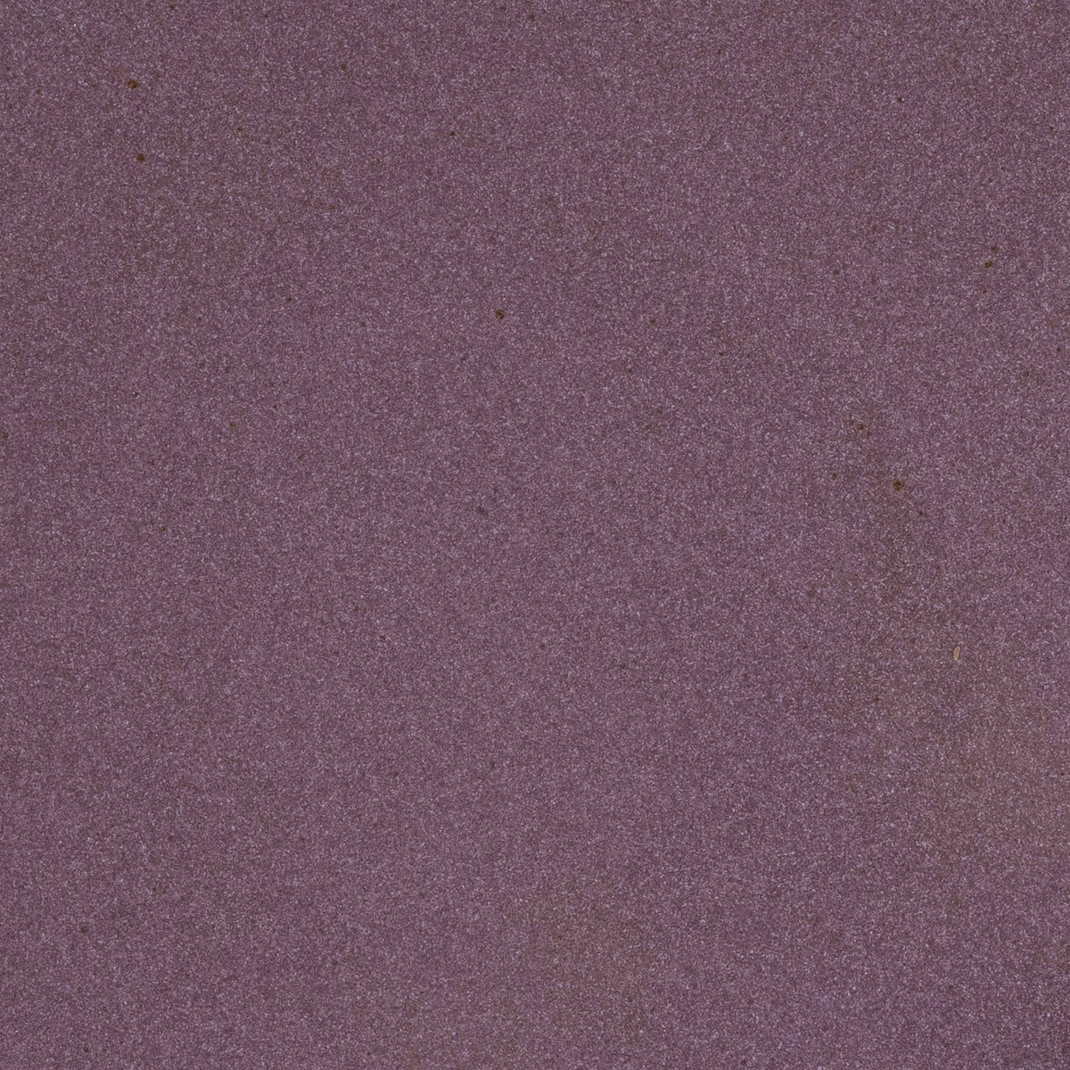 A closeup of a ceramic plate in a purple color with a soft, glowing sheen and iron speckles throughout