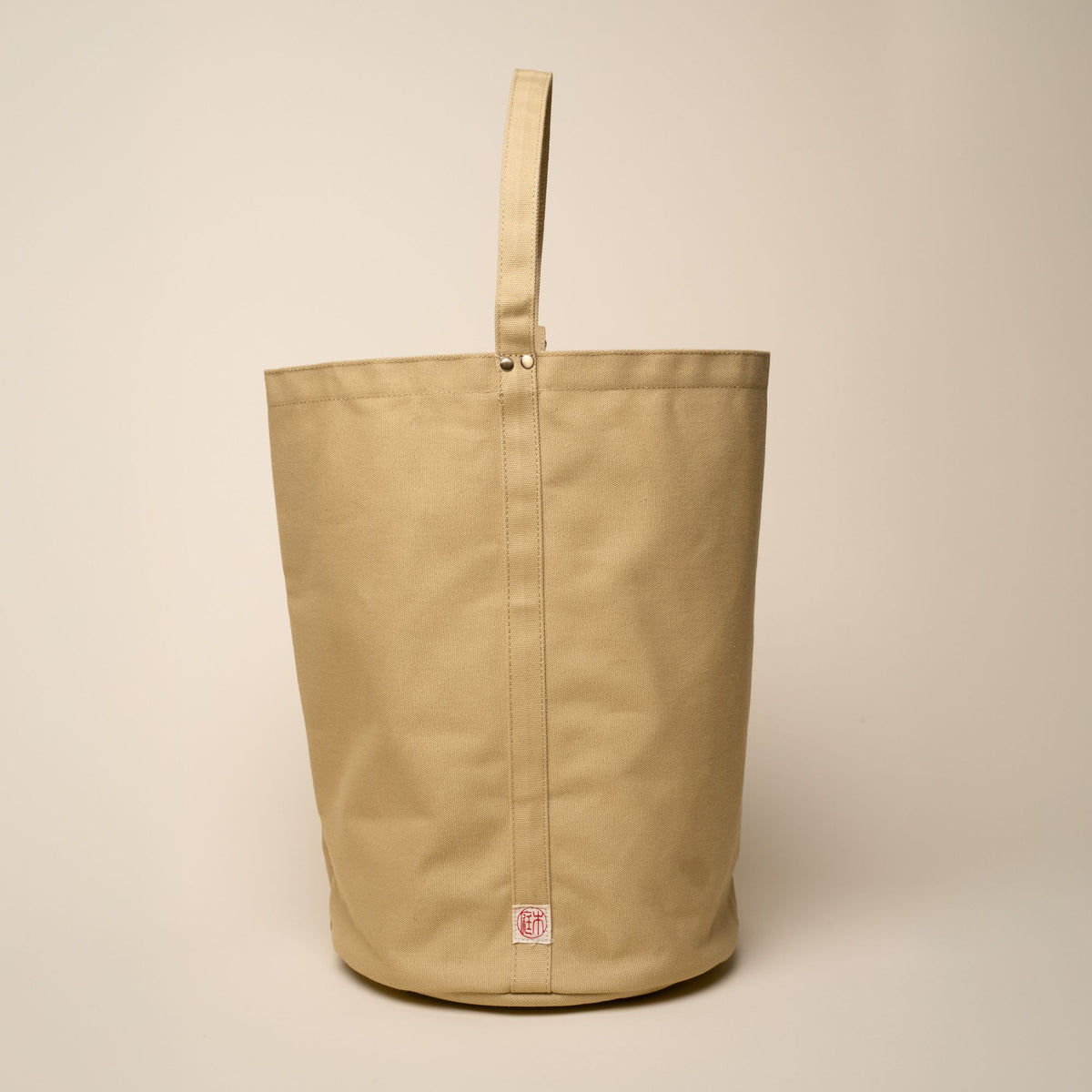 A large simple canvas bucket tote with the top handle propped up