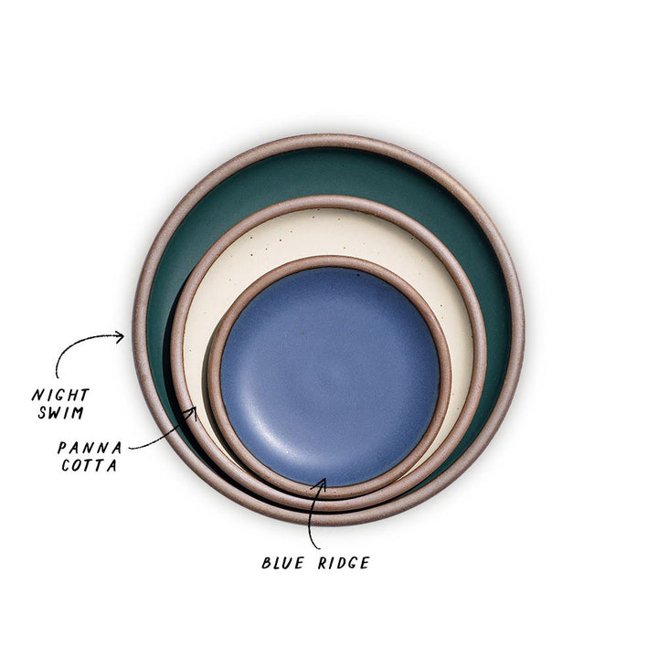 A stack of 3 plates in Dinner, Side, and Cake sizes in a dark teal, warm off-white, and navy colors.