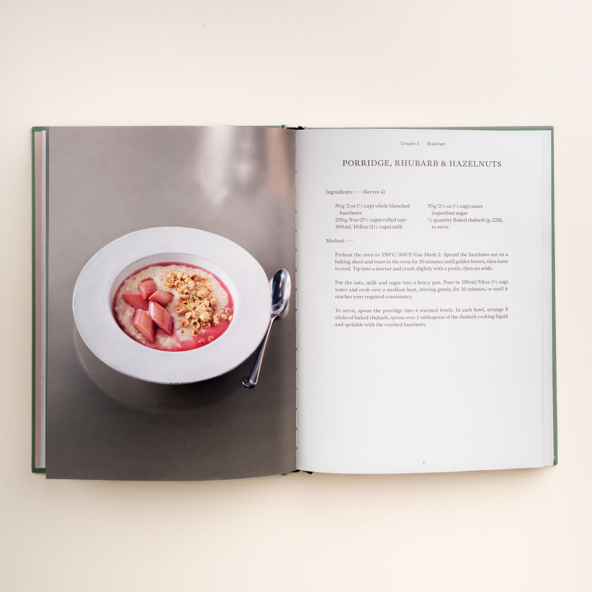 Open cookbook showing a recipe for porridge with rhubarb and hazelnuts beside a photo of the dish in a white bowl.