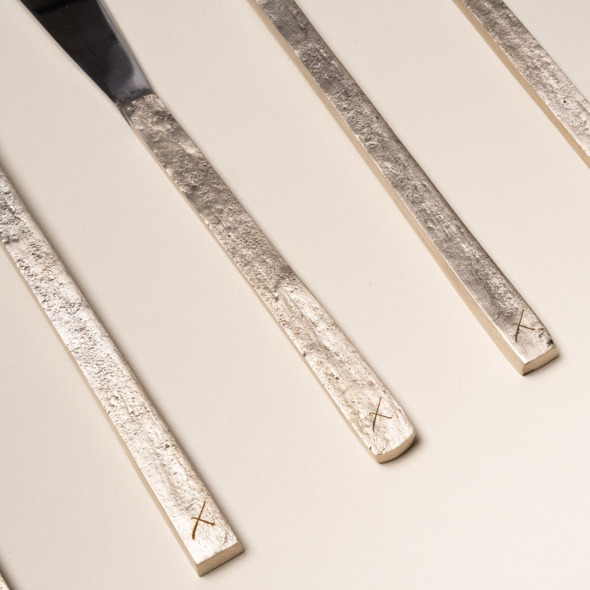 A detailed shot of La Tavola flatware handles, with lightly engraved 'X's in the brass.