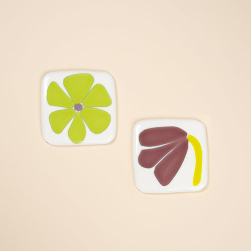 A pair of glass flower coasters, painterly simple floral shapes in neon green and purple