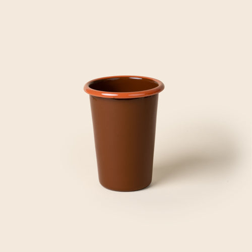 A tall red-brown enamel tumbler with an orange rim, set against a soft beige background.