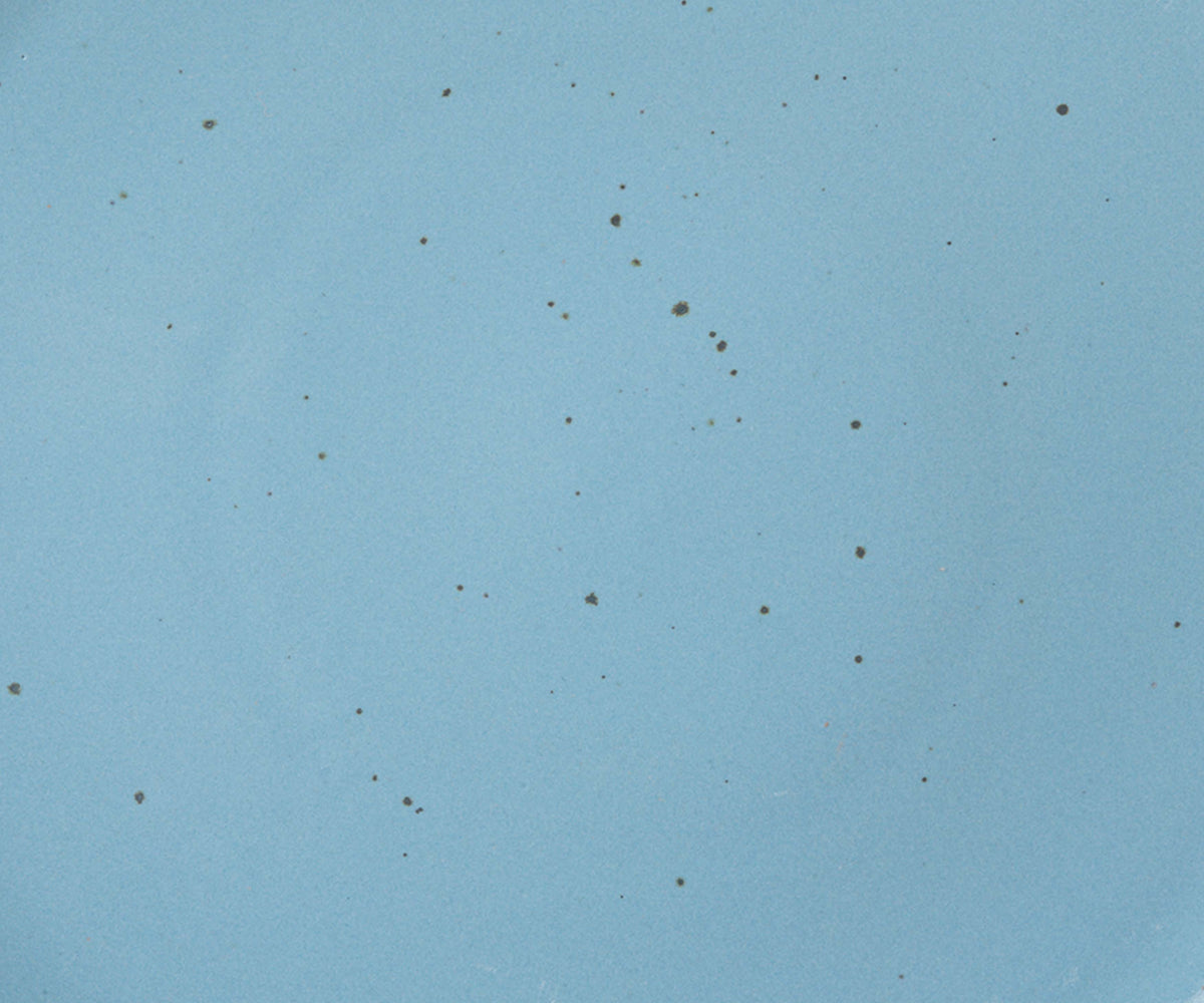 A closeup of a ceramic plate in a glossy cerulean color with iron speckles throughout