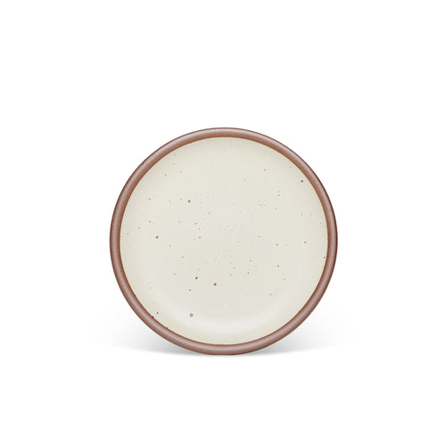 A medium sized ceramic plate in a warm, tan-toned, off-white color featuring iron speckles and an unglazed rim.