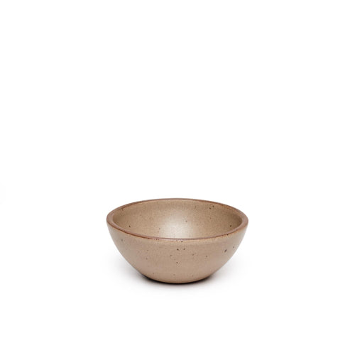 A small dessert sized rounded ceramic bowl in a pale warm brown color featuring iron speckles and an unglazed rim