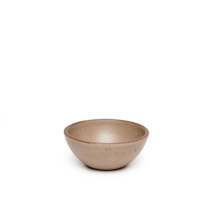 A small dessert sized rounded ceramic bowl in a pale warm brown color featuring iron speckles and an unglazed rim